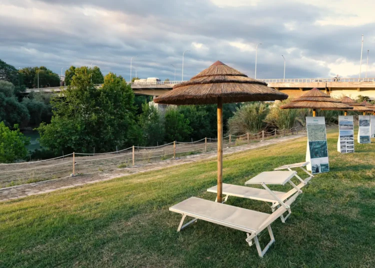 Ombrelloni di paglia e lettini sulla spiaggia lungo il Tevere, nell'area attrezzata Tiberis a Ponte Marconi
